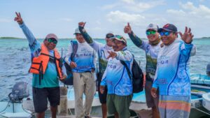 Smiling captains and Maya guides of Community Tours Sian Ka´an celebrating on the dock after a tour, boats and turquoise lagoon behind
