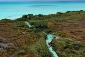 Aerial view of a kayaker inside the narrow turquoise ancient Maya canal winding through Sian Ka´an wetlands