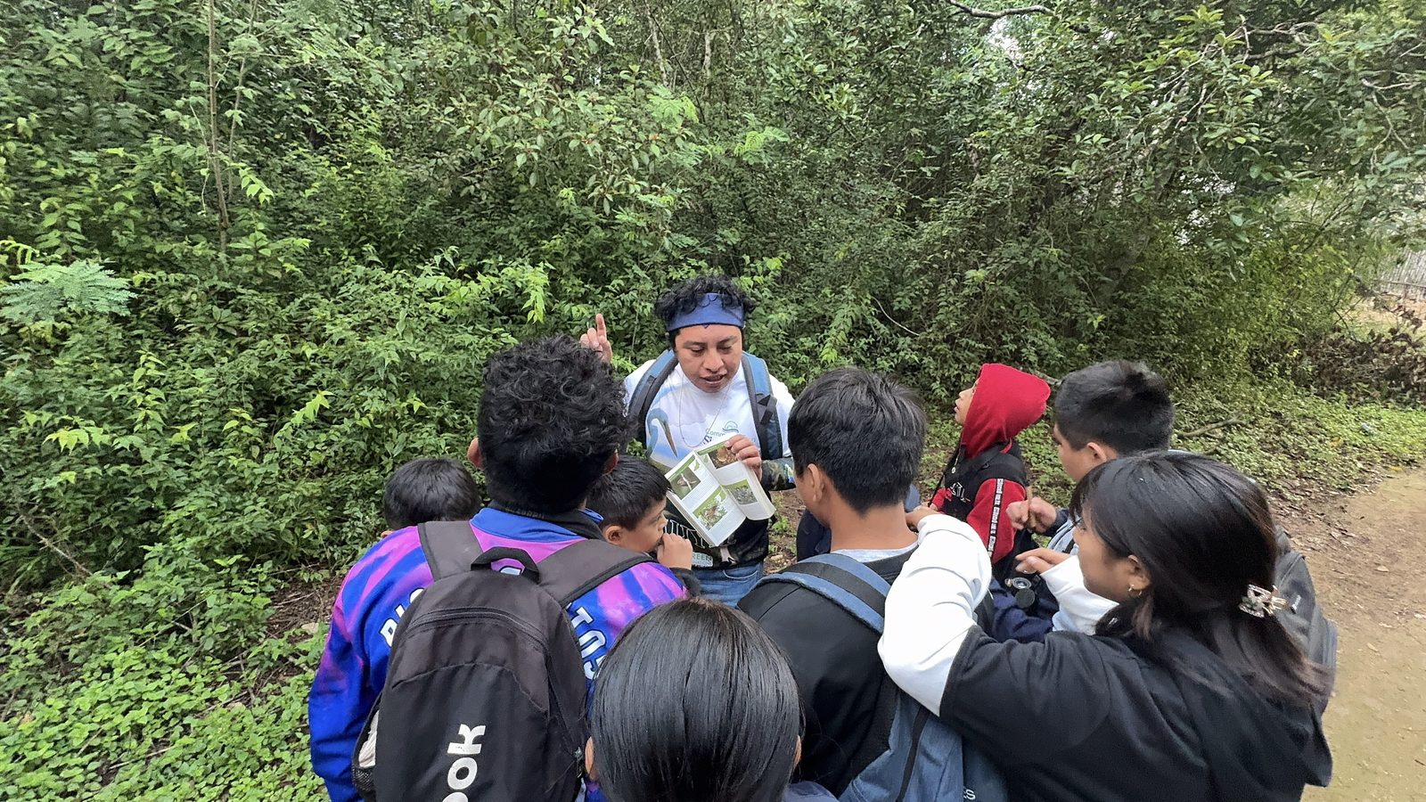 CTSK guide showing a bird field guide to a group of Maya children on a jungle trail