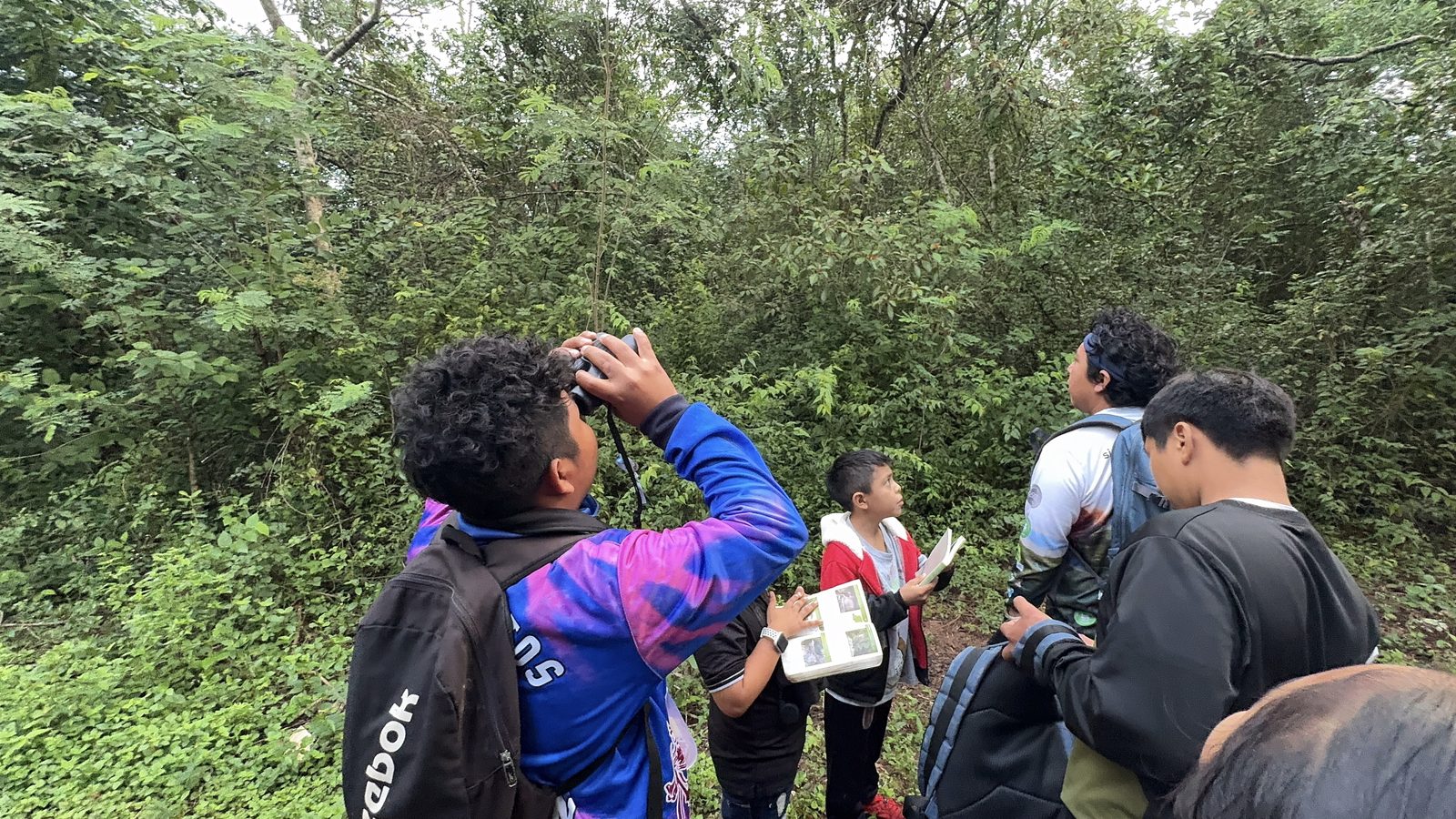 Maya children looking up to spot birds during the CTSK children s birding walk