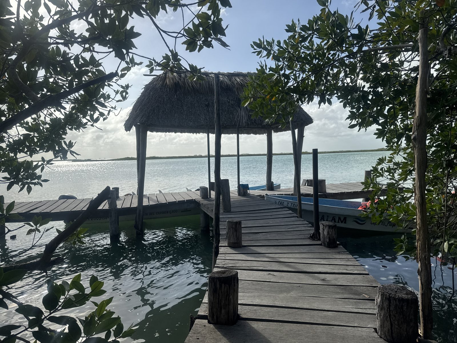 Thatched palapa dock over the calm turquoise water of the Muyil lagoon
