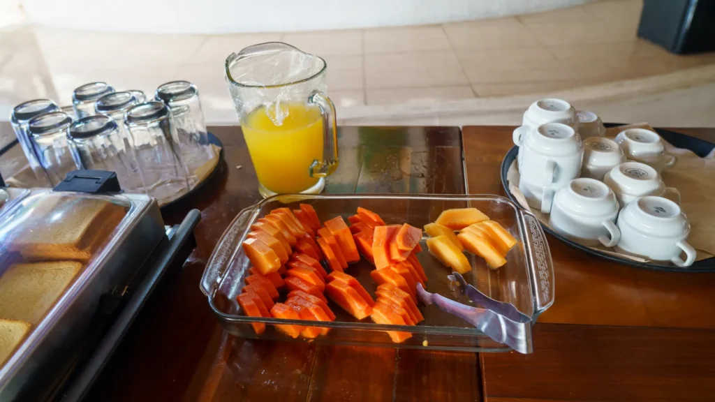 Breakfast table at the palapa with fresh orange juice, papaya and coffee cups