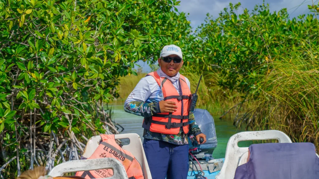 Captain in a life vest standing in his boat among mangroves