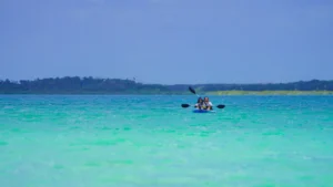 A single kayak on a vast turquoise lagoon under a clear sky