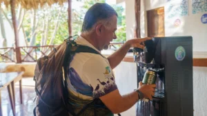 Visitor refilling a reusable bottle at the purified water station of the palapa