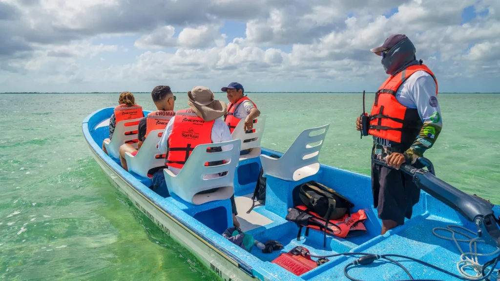 Visitors and captain in a boat on bright turquoise water, Sian Ka'an